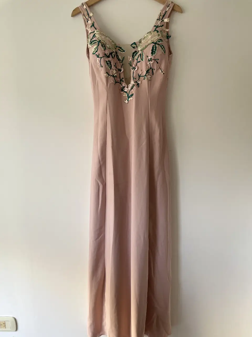Vestido largo de fiesta en tono rosa pálido, con delicados bordados florales en la zona del busto. Diseño elegante con escote en V y corte que estiliza la figura. Ideal para eventos especiales.
