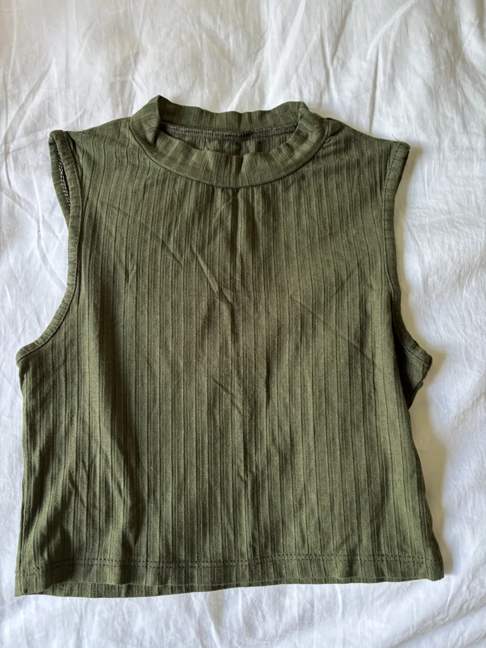 Musculosa verde con cuello alto y textura acanalada.