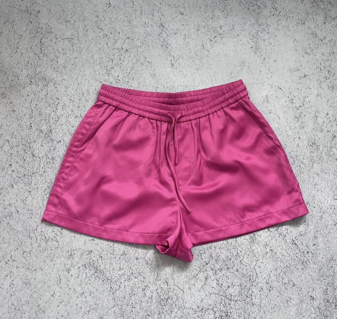 Shorts de satén color fucsia con cintura elastizada y cordón de ajuste. Posee bolsillos laterales. Talle 38. Medidas: 35 cintura (cede a 48 porque tiene elástico) y 57 cadera