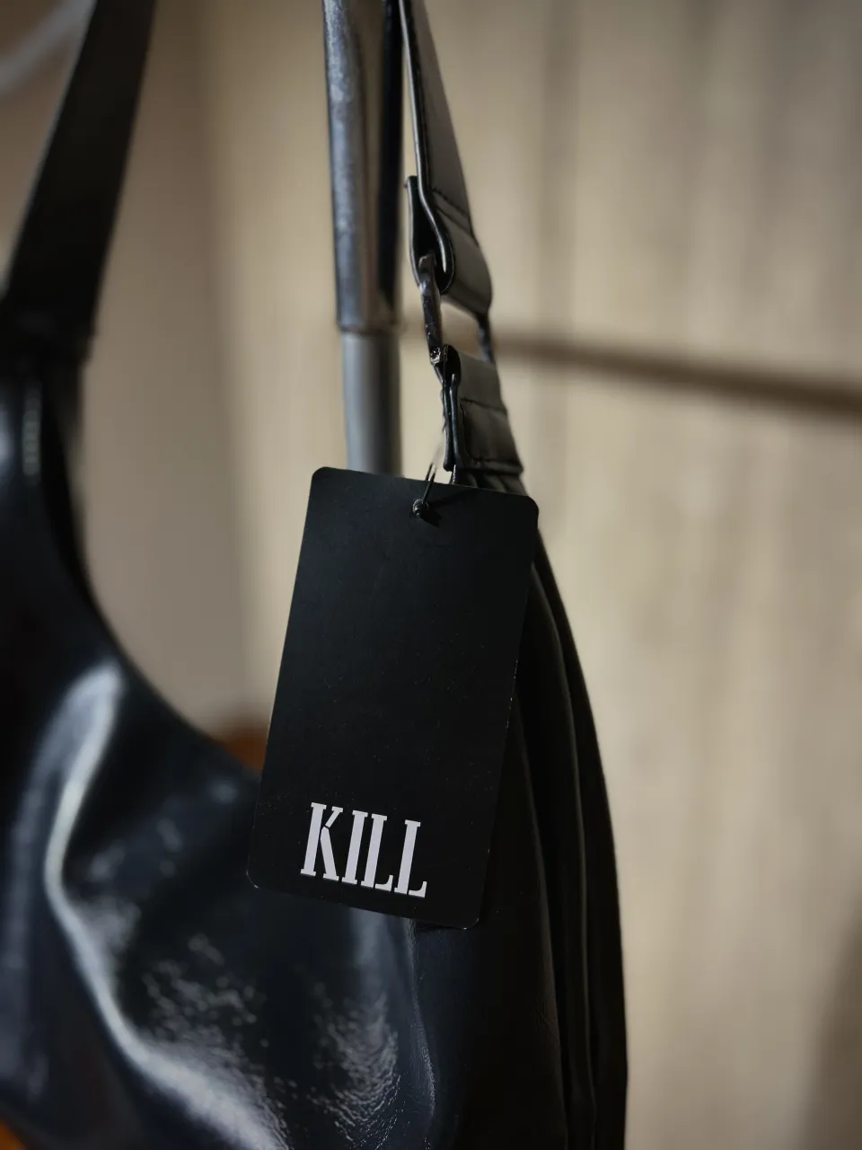 Cartera negra de cuero sintético con etiqueta. marca "KILL" en blanco. El interior cuenta con un bolsillo con cierre y otro abierto.