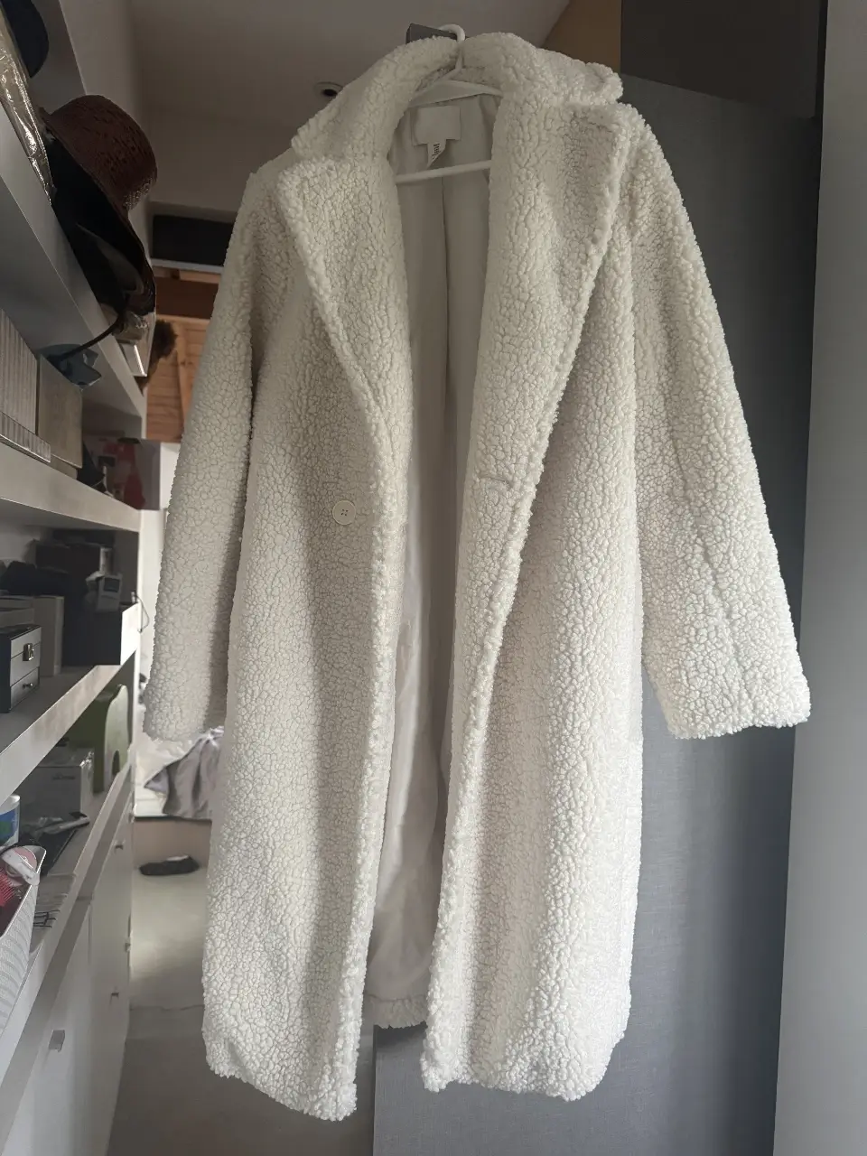 Tapado largo de mujer, color blanco, estilo teddy, con cuello solapa y un botón. Ideal para el invierno.