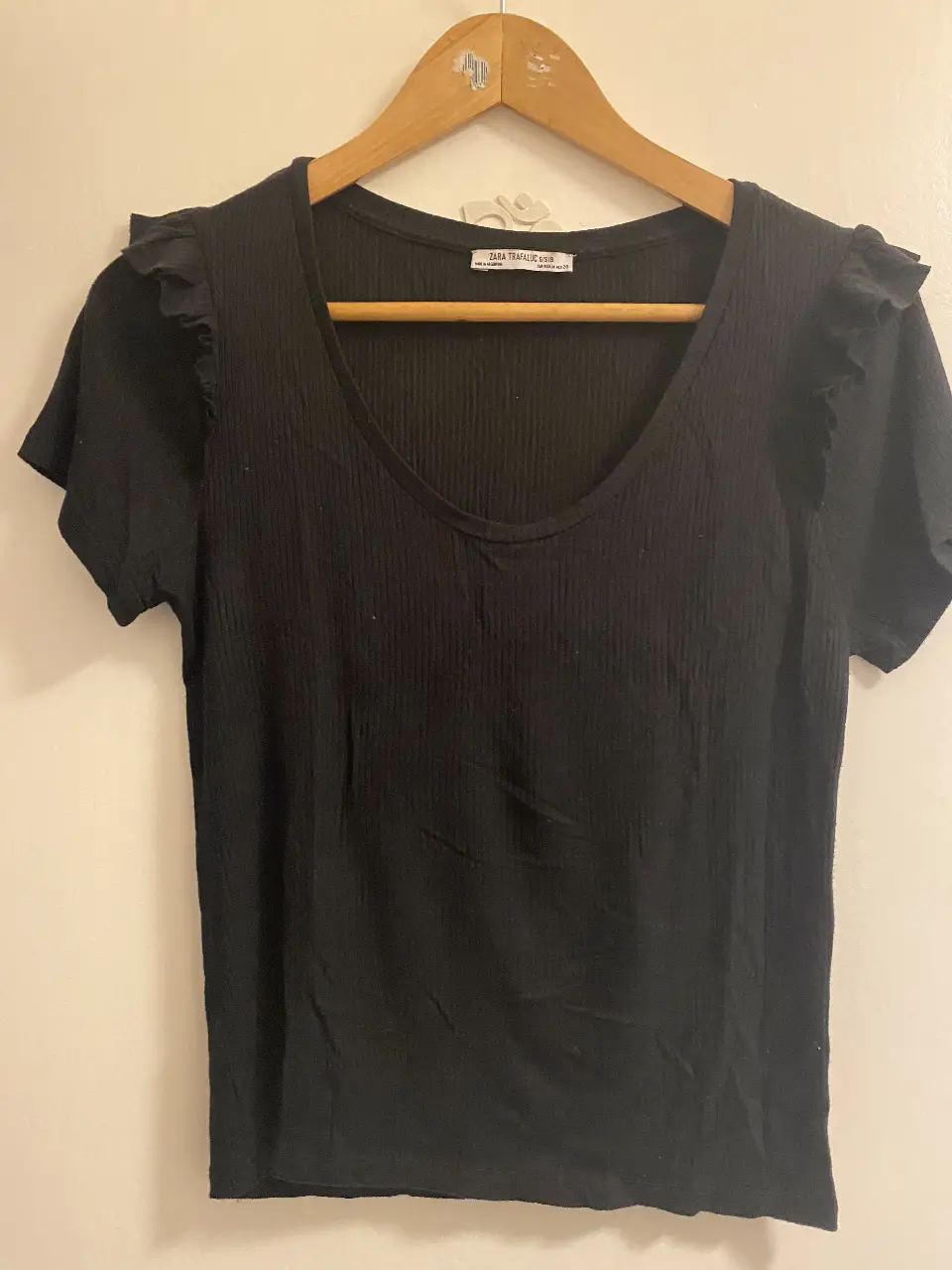 Remera negra de Zara Trafaluc con detalle de volados en las mangas. Corte ajustado y escote en U. Ideal para un look casual y moderno.