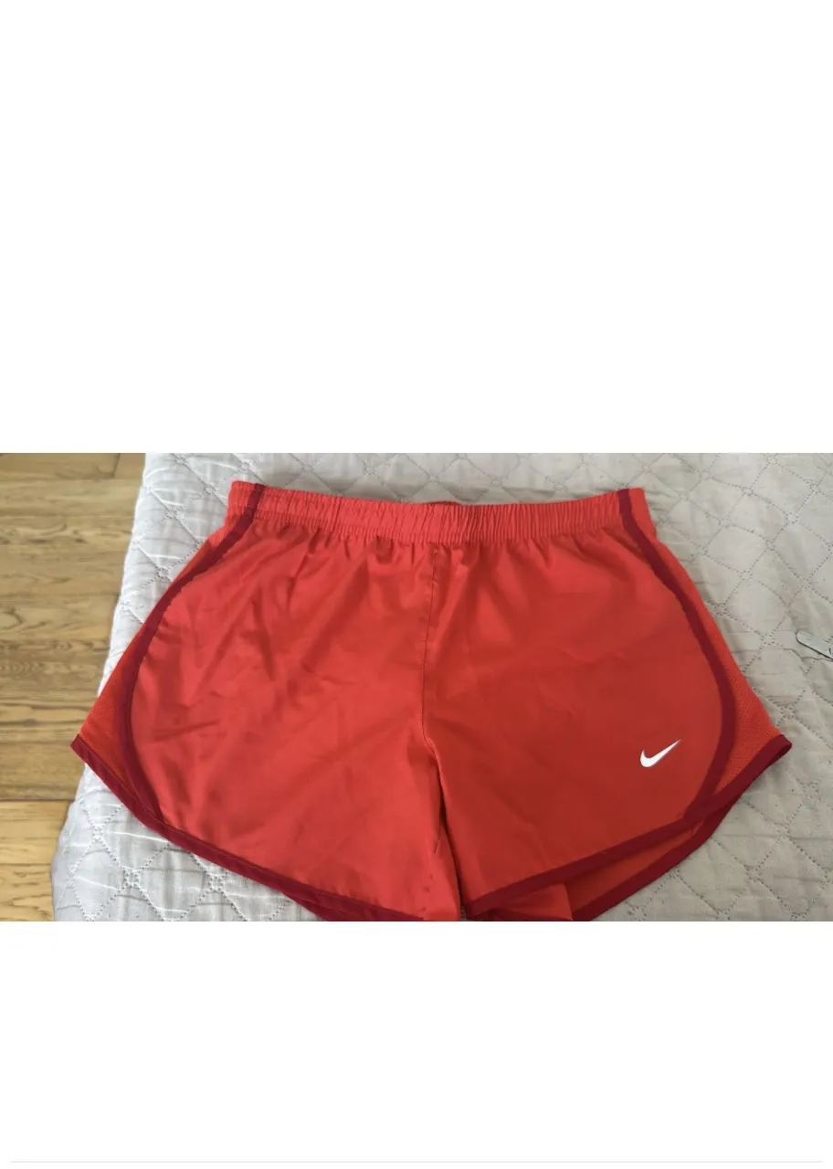 Shorts deportivos Nike en color rojo/naranja vibrante, perfectos para entrenar o para un look casual y cómodo. Cuentan con el icónico logo de Nike en blanco en la parte delantera.