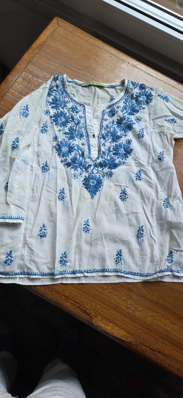 Blusa blanca con bordados florales en azul. Ideal para un look casual y fresco.