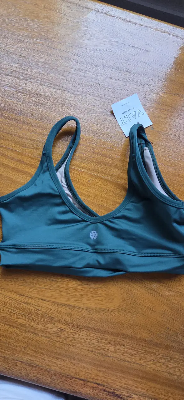 Top deportivo verde oscuro de la marca VALT, ideal para actividades de bajo impacto. Diseño con espalda cruzada y escote en V.