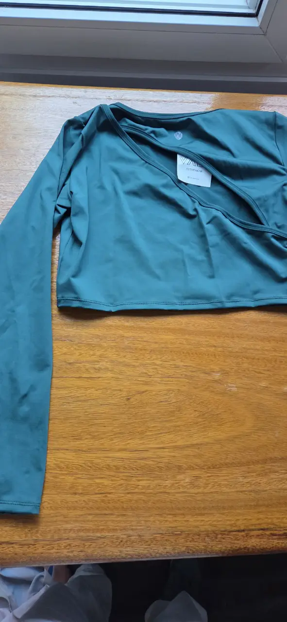 Top deportivo de manga larga en color verde oscuro, ideal para actividades de alto rendimiento. Diseño envolvente y ajuste ceñido para mayor comodidad y soporte.