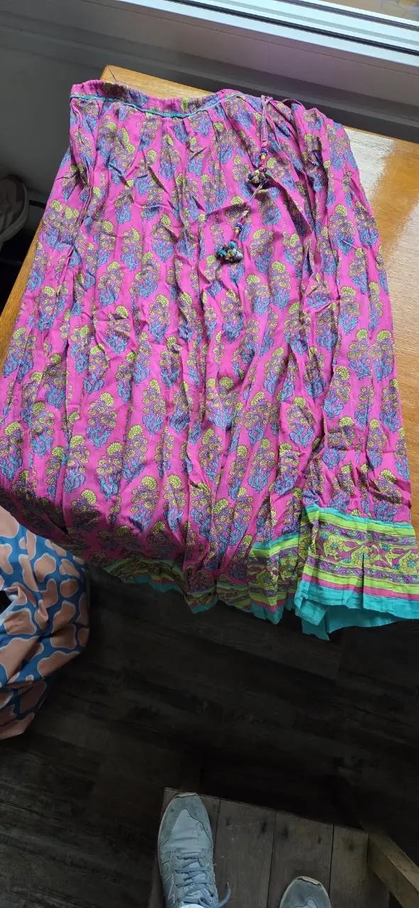 Pollera larga de tela con estampado floral en tonos rosa y verde. Estilo boho, ideal para un look casual y fresco.