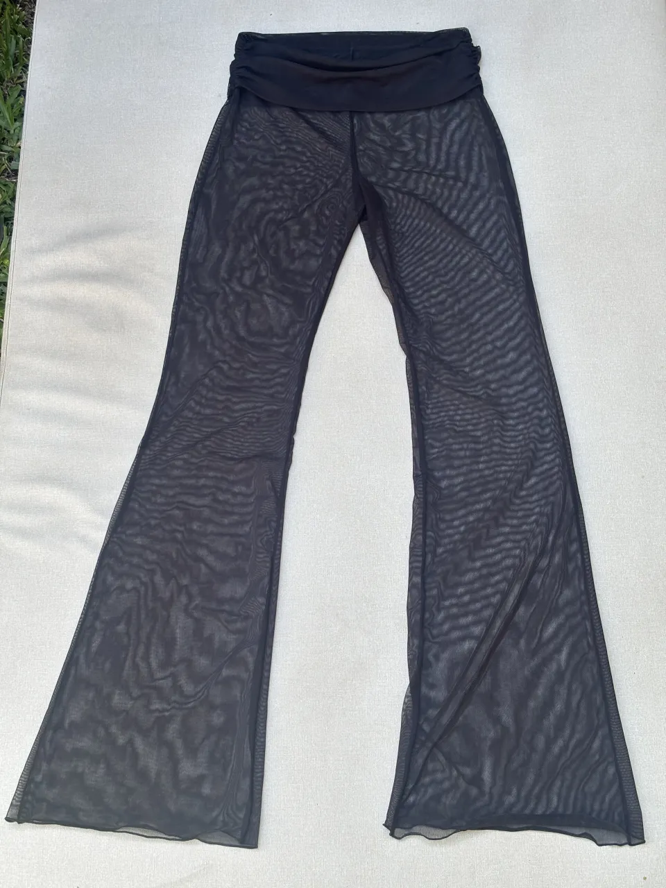 Pantalón de red negro, tiro alto, con corte acampanado. Ideal para usar sobre bikinis o como parte de un look de festival.