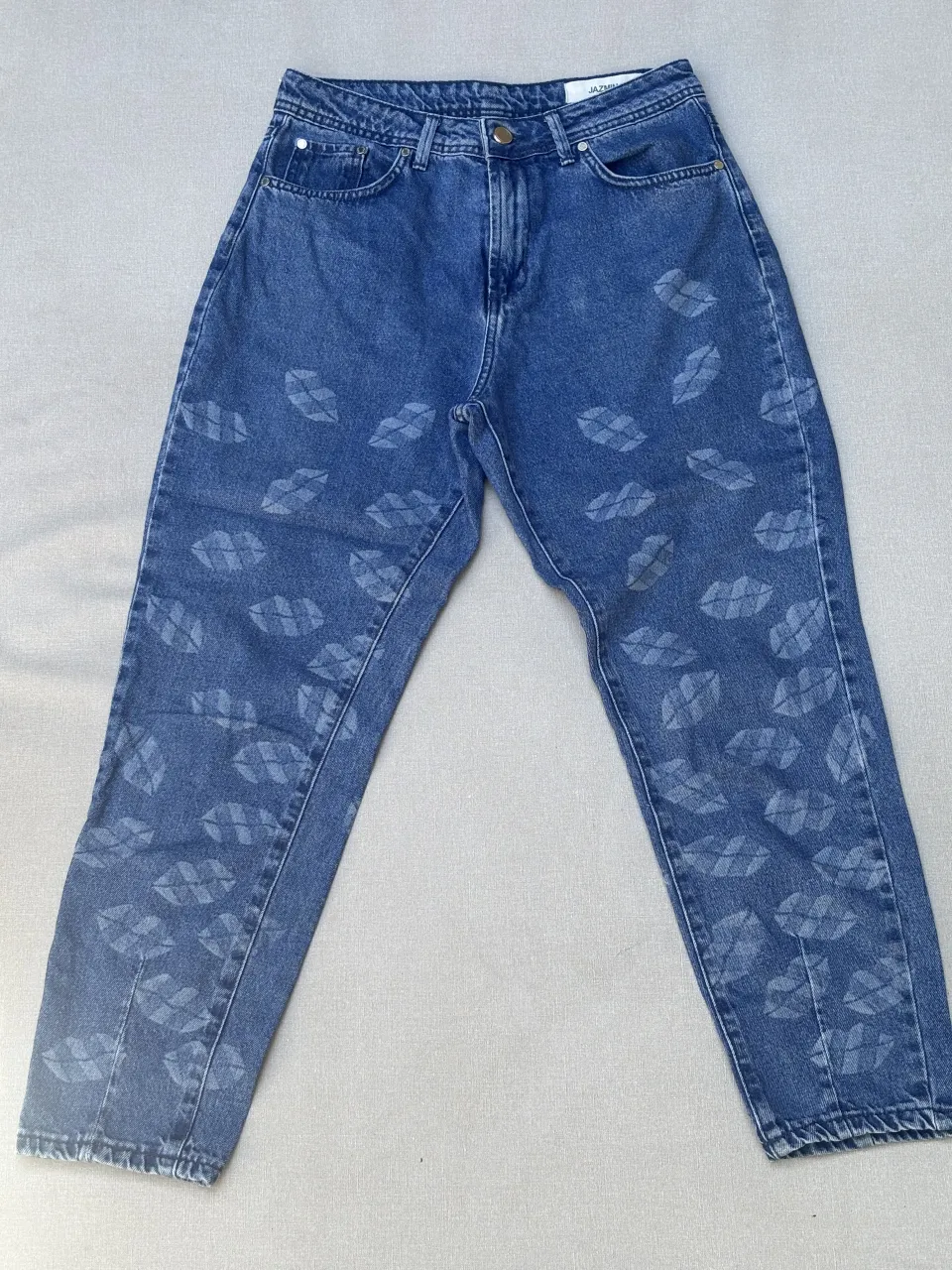 Jeans de tiro alto con estampa de labios en toda la prenda. Un modelo súper canchero y original para destacar tu outfit. Ideales para un look casual y divertido.