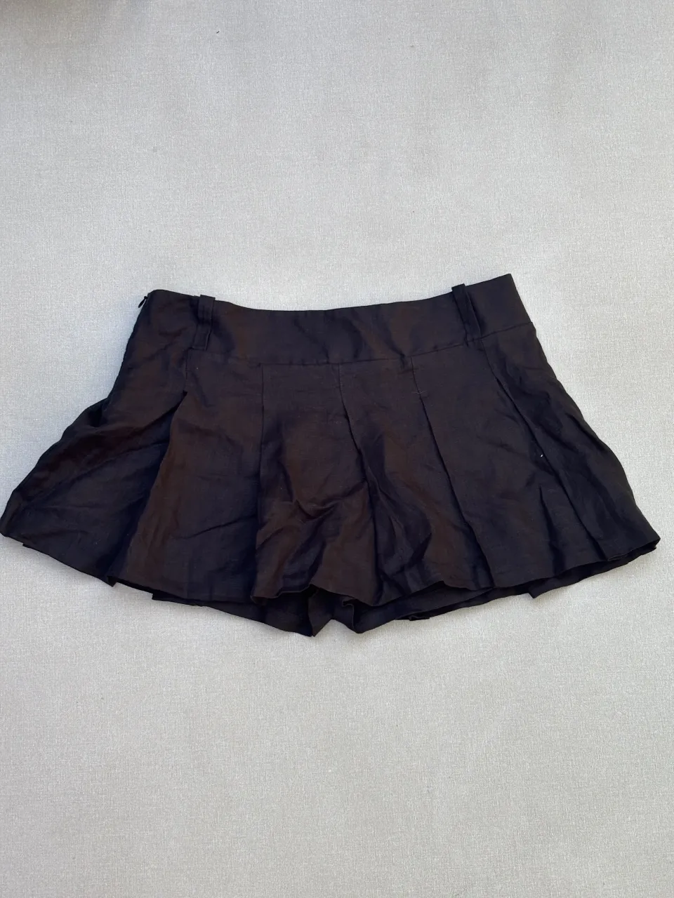 Pollera corta negra con tablas 100% lino, ideal para un look casual y moderno. Perfecta para combinar con remeras o tops.