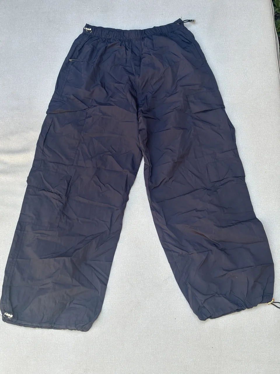 Pantalón cargo negro, tiro alto, con cordón ajustable en la cintura y en los tobillos. Diseño ancho y cómodo, ideal para un look urbano y relajado.