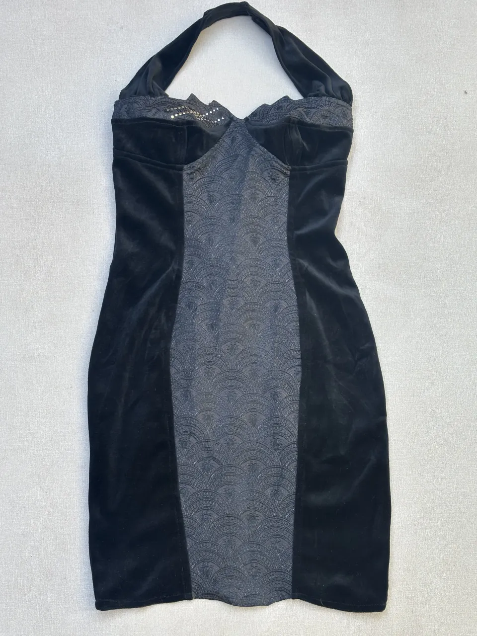 Vestido negro corto, estilo halter con detalles de encaje y brillos en el busto. Diseño ajustado al cuerpo con un panel central texturizado. Ideal para una noche especial o una fiesta.

Talle 12