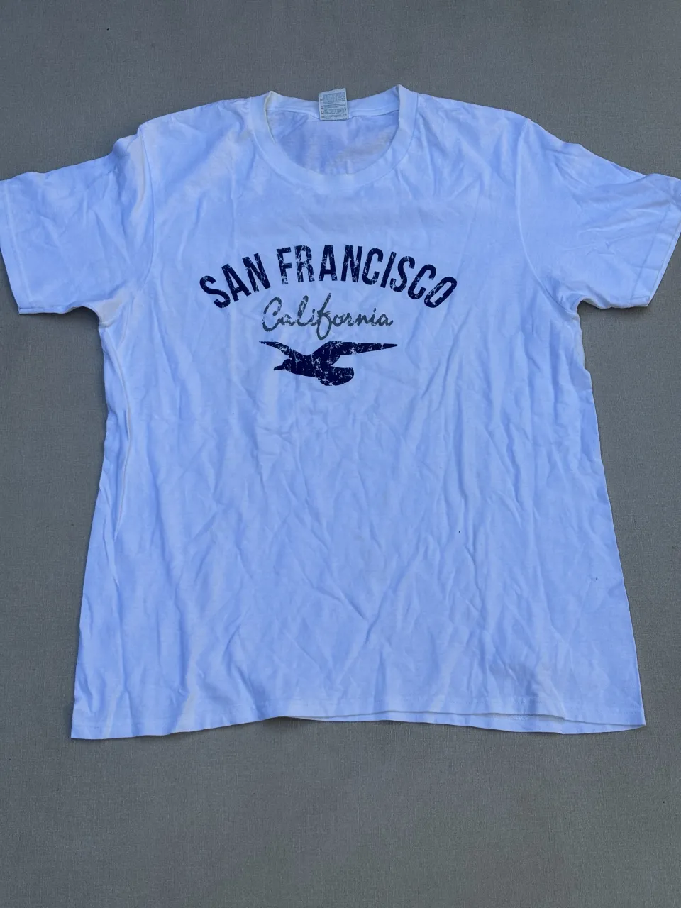 Remera blanca de manga corta con estampa "San Francisco California" y un ave en la parte delantera. Ideal para un look casual y relajado.
