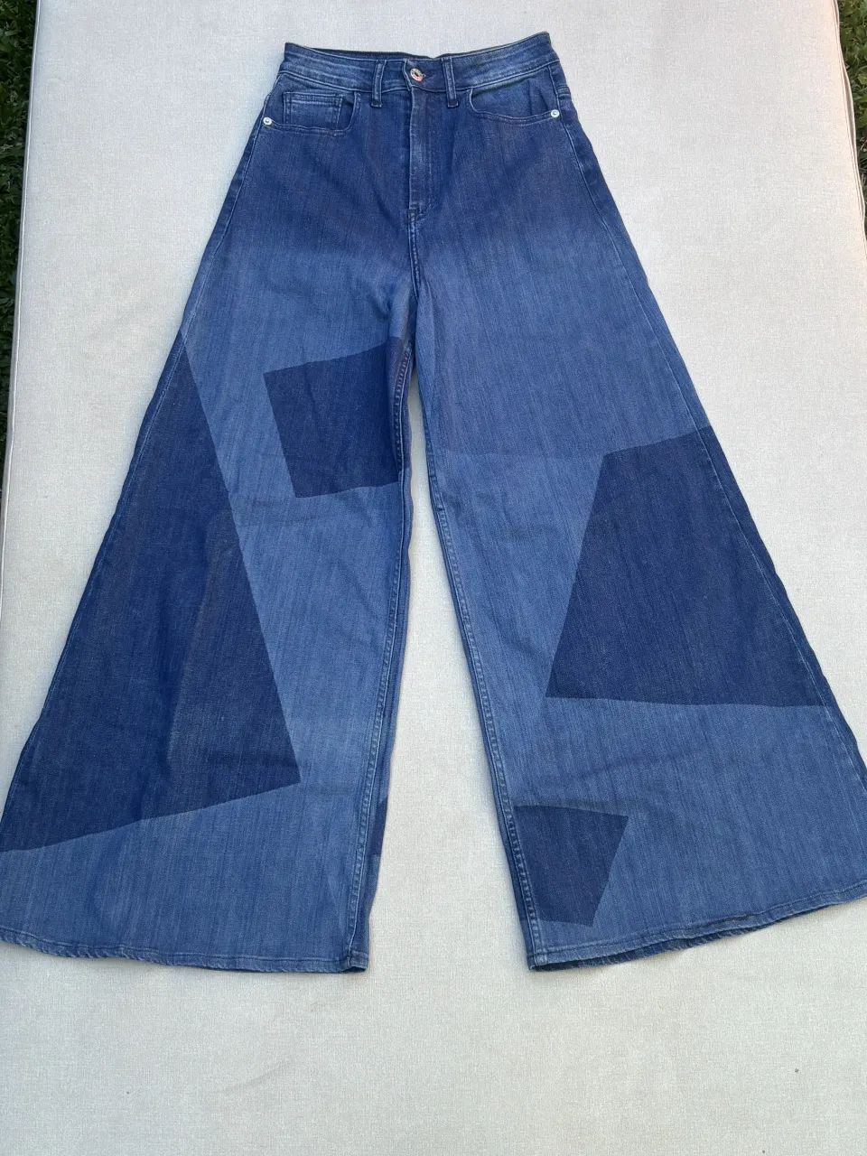 ¡Impresionantes jeans palazzo de tiro alto con un diseño patchwork único en denim! Estos pantalones son perfectos para un look moderno y canchero. Su corte ancho y la combinación de tonos de azul le dan un toque súper original. Ideales para combinar con tops o remeras ajustadas.