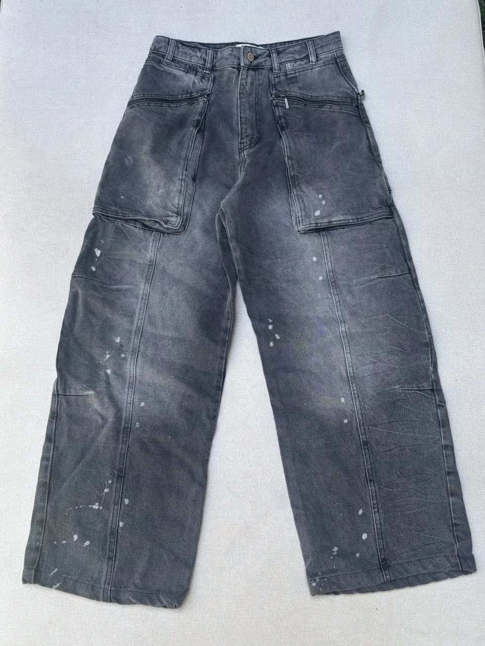 Jean ancho, con detalles de pintura blanca y bolsillos cargo con cierre. Un estilo urbano y moderno, perfecto para un look canchero.

Detalle: mancha visible en la última foto