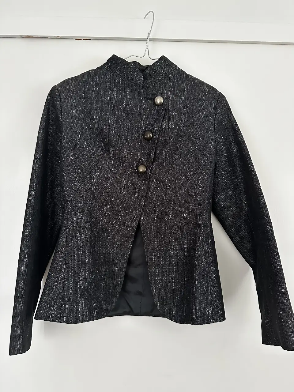 Elegante blazer negro con diseño asimétrico y botones metálicos. Ideal para un look sofisticado y moderno.
