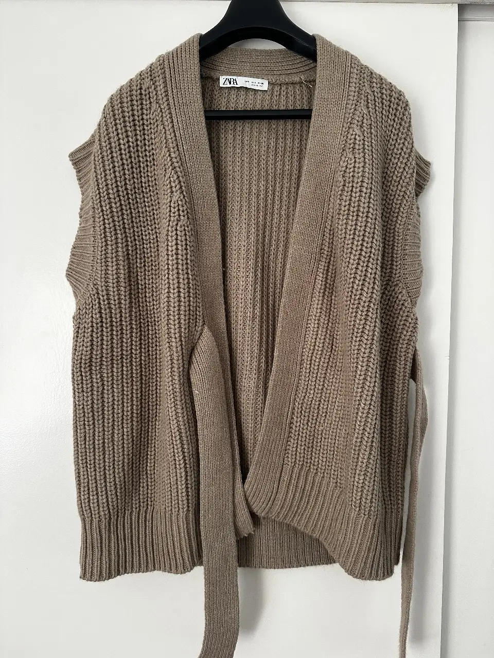 Chaleco tejido de punto grueso, con diseño envolvente y cinturón para ajustar. Ideal para un look casual y abrigado.