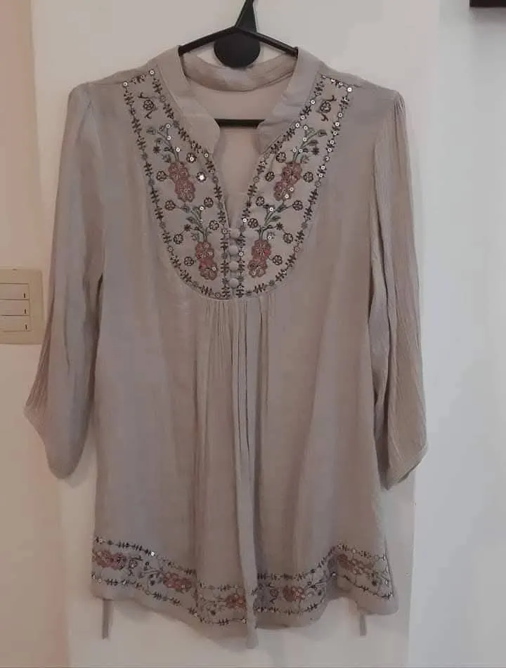 Blusa de mujer en tono beig con detalles bordados y lentejuelas. Diseño con cuello en V y mangas 3/4. Ideal para un look casual y elegante.