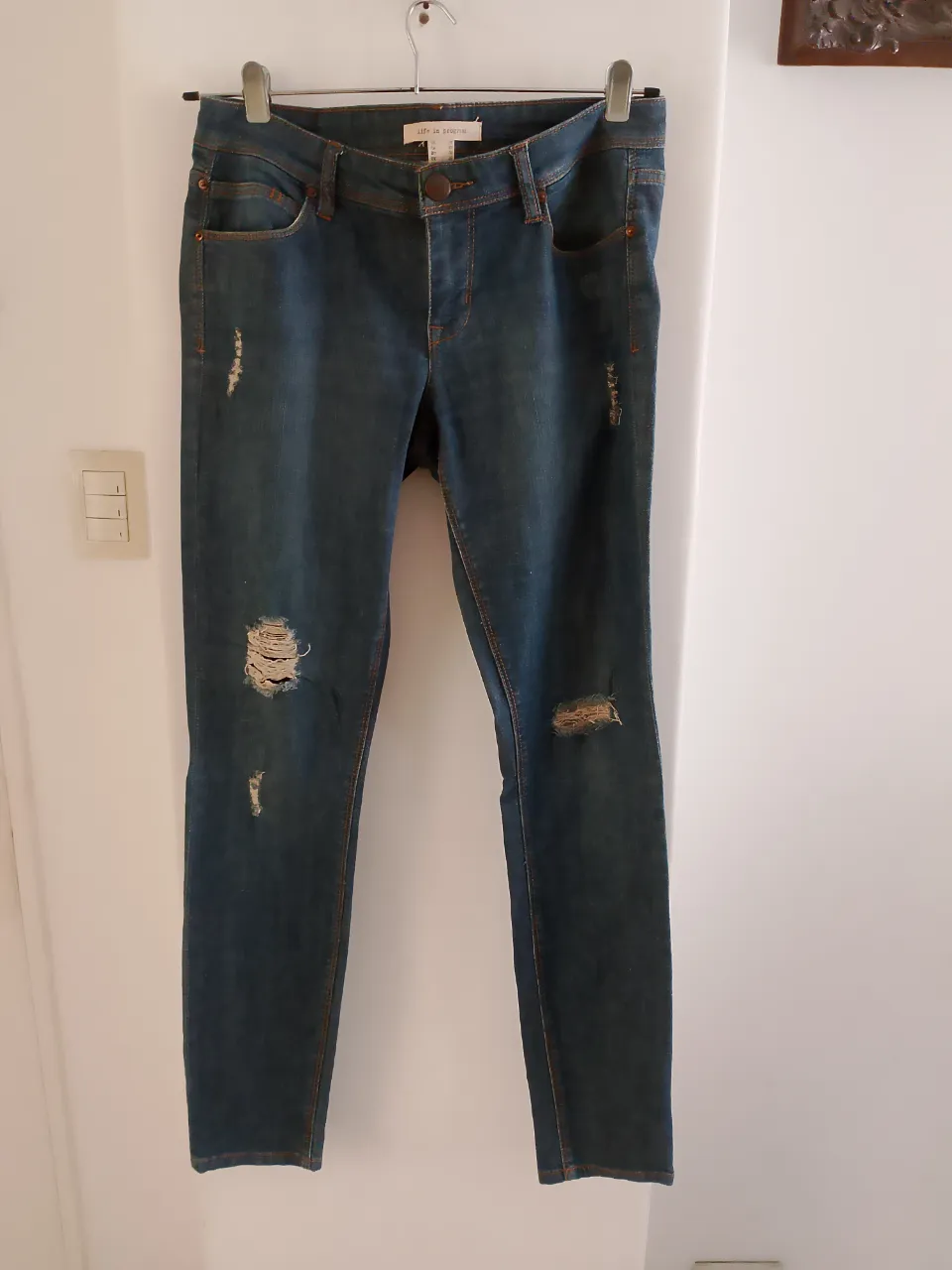 Jeans de mujer, tiro medio, con roturas en las rodillas. Tono azul oscuro. Marca Life in Progress.