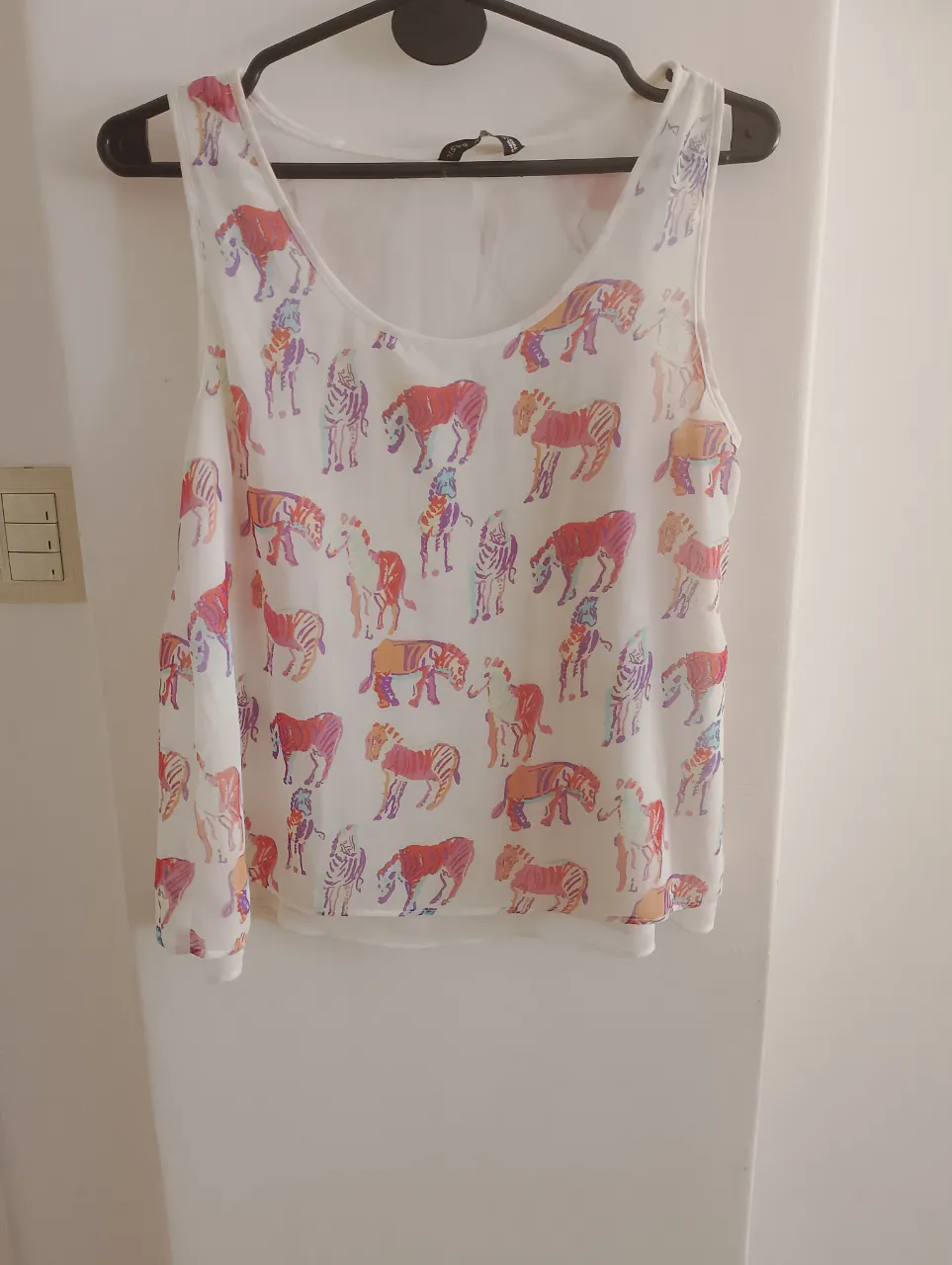 Blusa de mujer con estampado de cebras en tonos vibrantes. Diseño sin mangas, ideal para un look fresco y moderno. Perfecta para combinar con jeans o faldas.