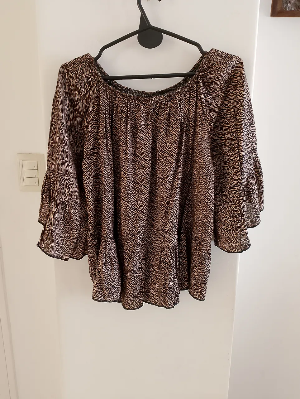 Blusa de mujer con estampado de cebra en tonos marrones y negros. Diseño con mangas amplias y volantes, ideal para un look casual y con estilo.