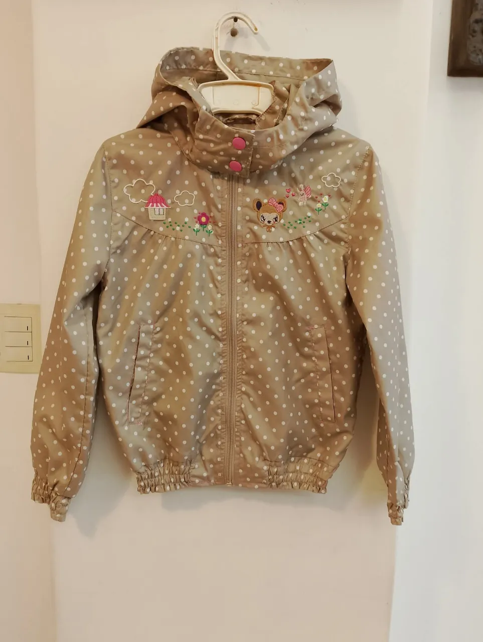 Campera para niña con diseño de lunares y bordados. Ideal para proteger del viento y la lluvia ligera. Cuenta con capucha y cierre frontal.