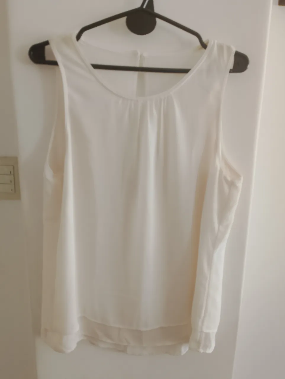 Blusa color crema sin mangas, con detalle de fruncido en el frente y abertura en la espalda. Ideal para un look fresco y elegante.