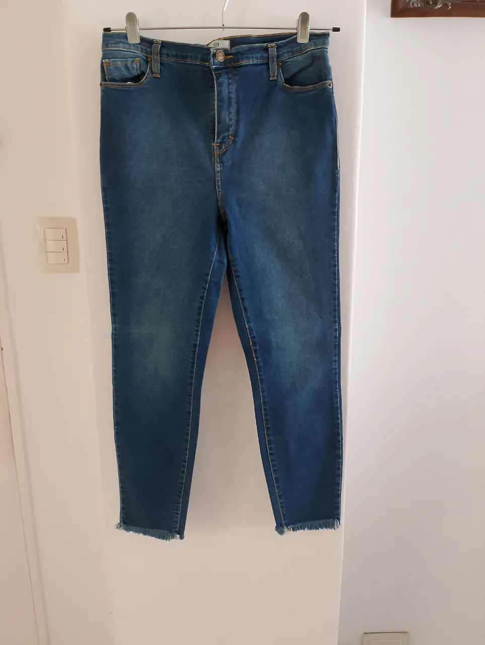 Jeans de mujer tiro alto, con un corte recto y detalles de flecos en el bajo. Un clásico de la moda, ideal para un look casual y versátil.