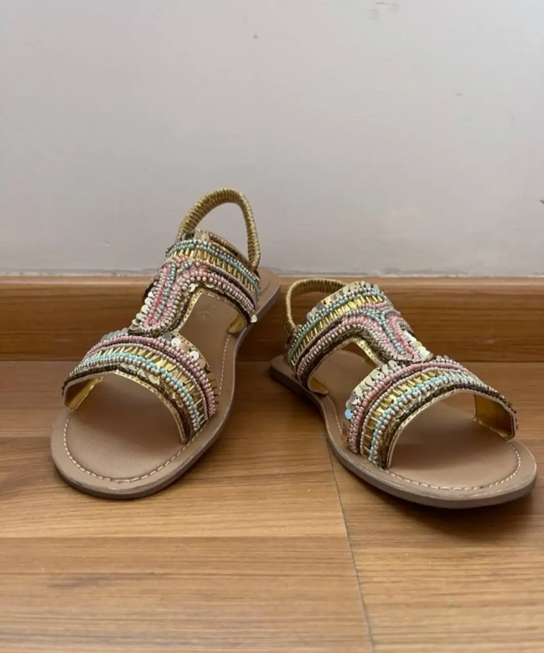 Sandalias doradas con detalles de pedrería en tonos pastel. Perfectas para un look de verano elegante y cómodo.