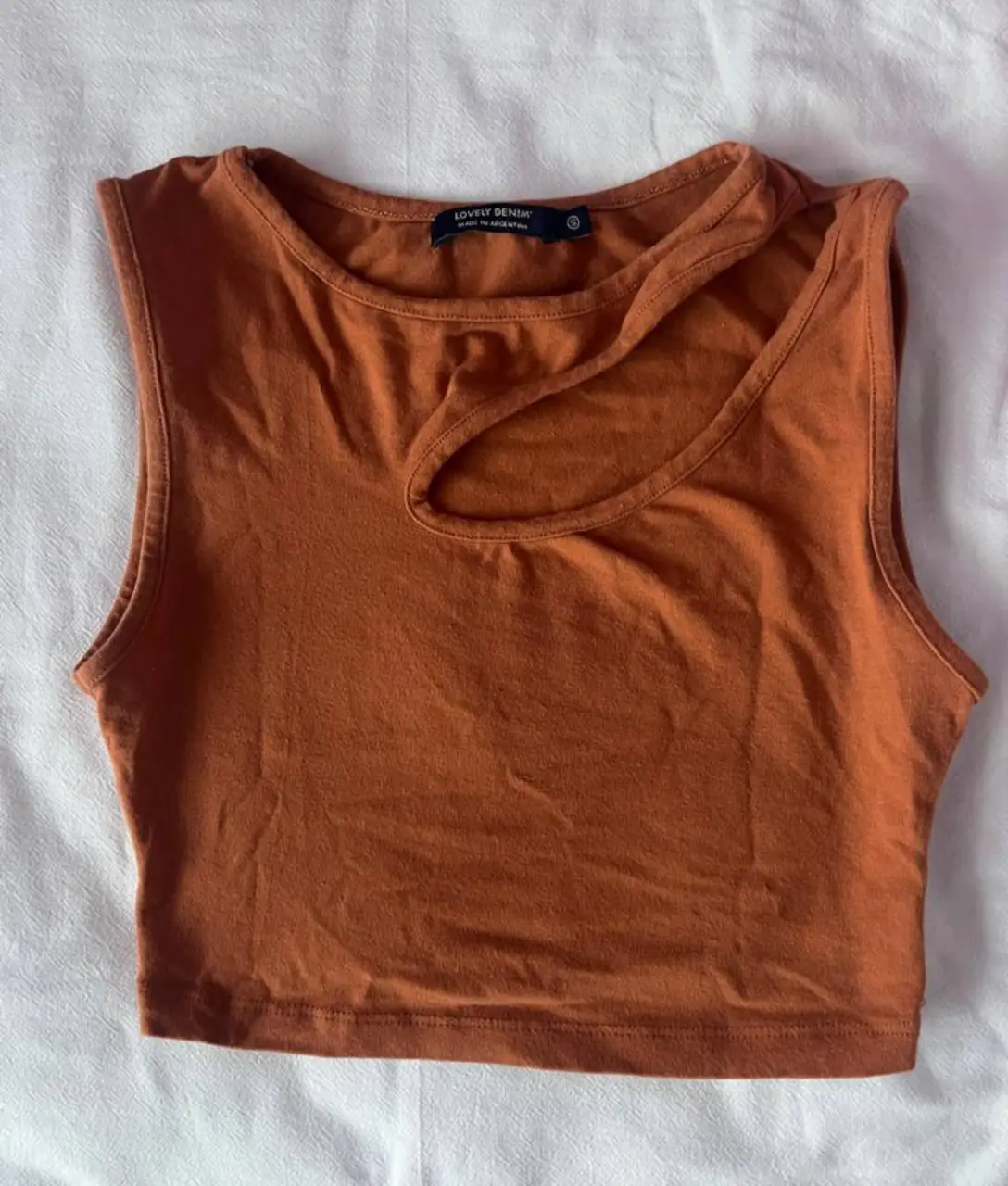 Top de mujer color marrón con diseño asimétrico en el cuello. Ideal para un look casual y moderno.