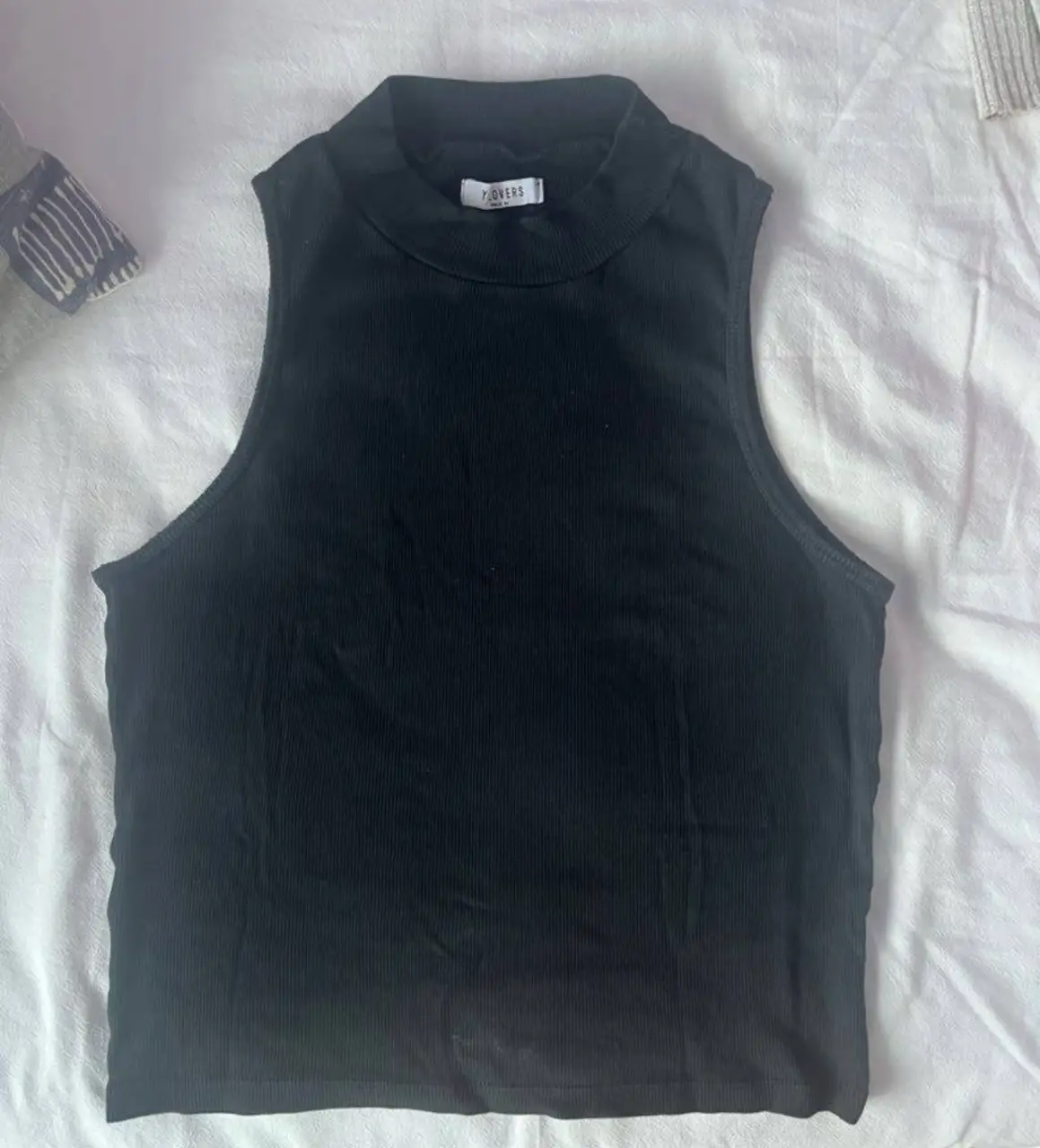 Top negro de cuello alto, sin mangas, ideal para un look casual y moderno. Perfecto para combinar con jeans o pantalones de vestir.