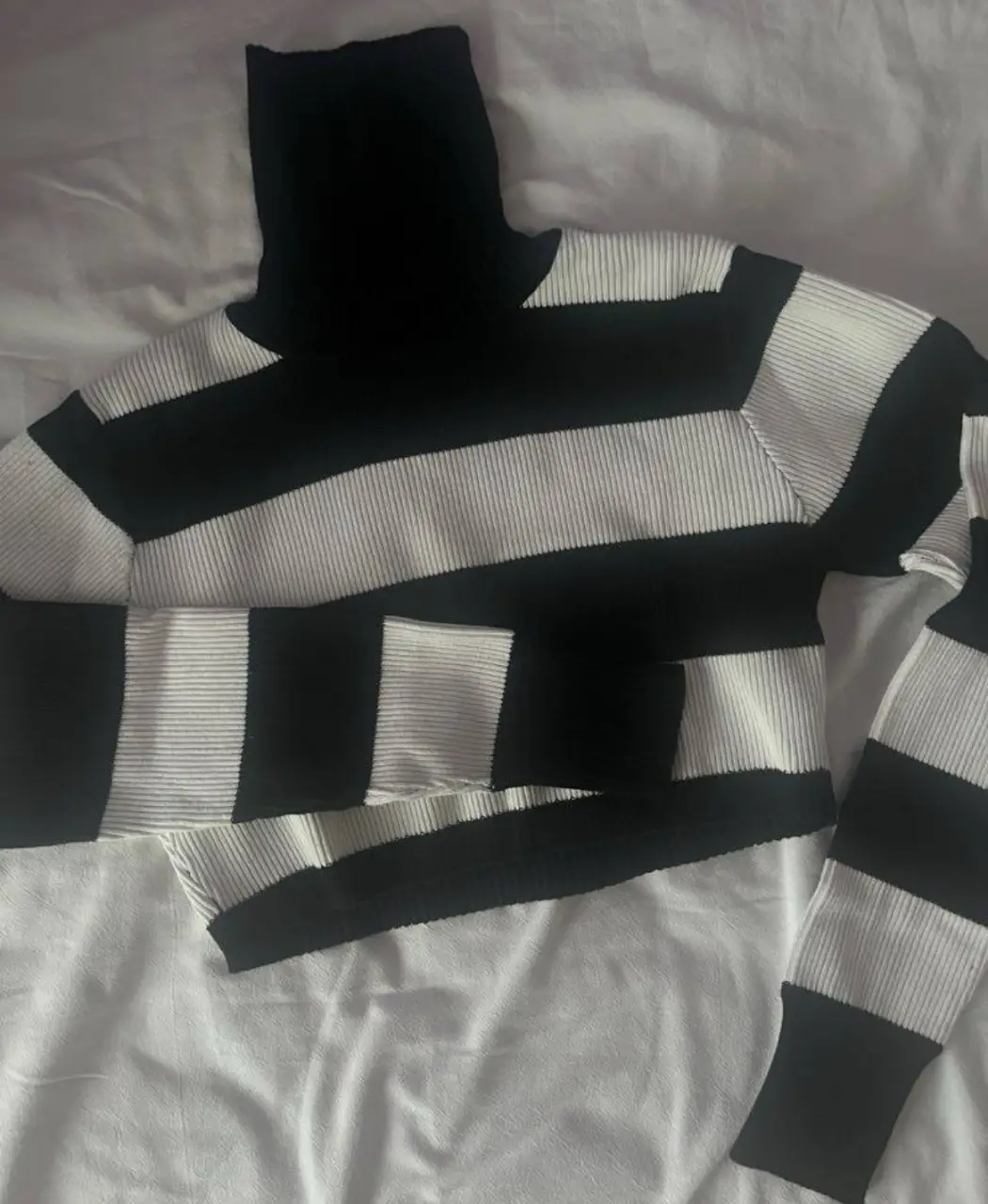 Sweater polera a rayas horizontales en blanco y negro. Cuello alto. Ideal para un look casual y moderno.