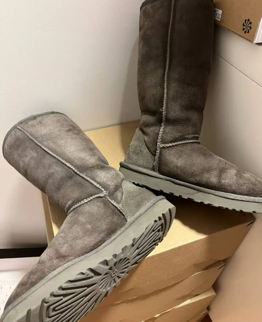 Botas UGG altas de gamuza gris, ideales para el invierno. Cómodas y abrigadas, perfectas para un look casual.