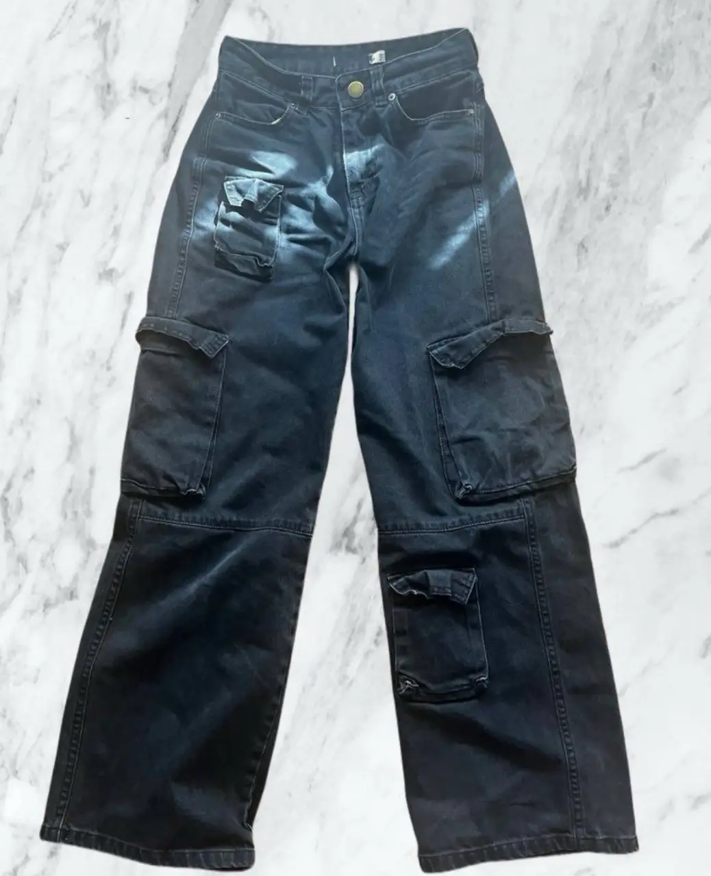 Pantalón cargo negro de jean, tiro medio y corte ancho. Con bolsillos laterales y en las piernas, ideal para un look urbano y cómodo.