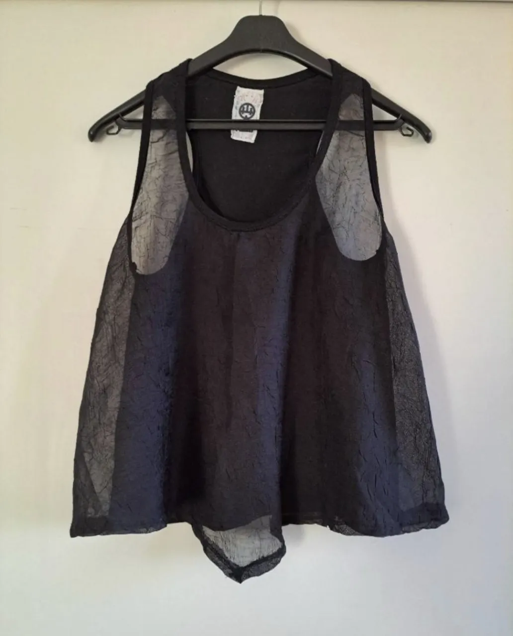 Musculosa negra con detalles de tela transparente -de textura arrugada- en los breteles y en la parte inferior.
(Se puede combinar con una musculosa básica).