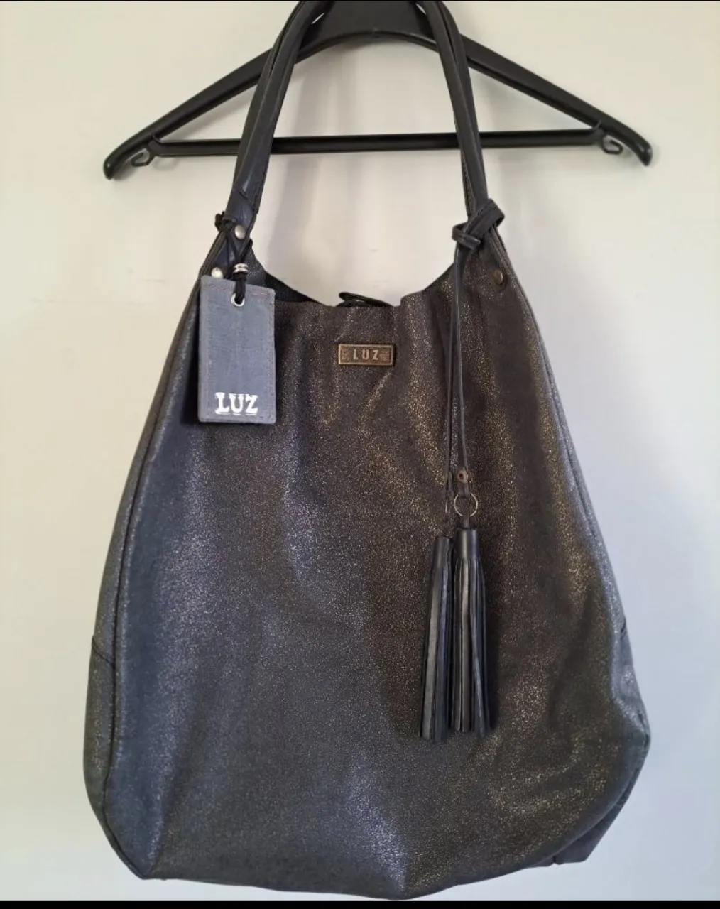 Cartera de marca "LUZ" de cuero negro con detalles dorados y flecos colgantes (grande, amplia, cómoda).
Cierra con 2 broches de manera cruzada por lo que queda bien cerrada. 
En su interior contiene un sobre con cierre (tipo monedero) amarrado al mismo cuero de la cartera. 
Es de cuero legítimo y no es forrada en su interior.                                                                                                 
Ideal para regalar o regalarte!!! 😉