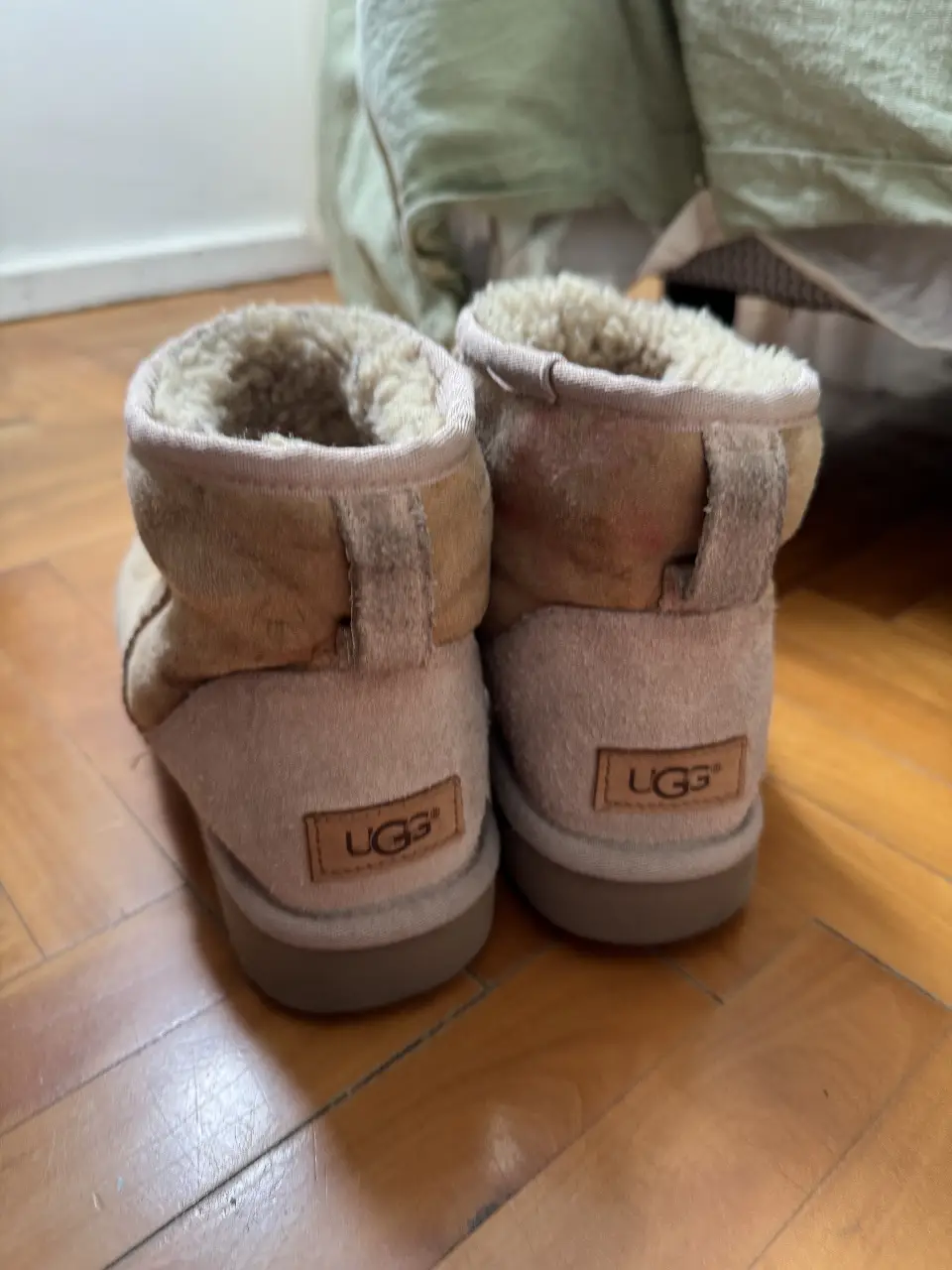 Botas UGG de gamuza color marrón claro, con detalles de la marca en la parte trasera. Ideales para un look casual y abrigado en invierno.