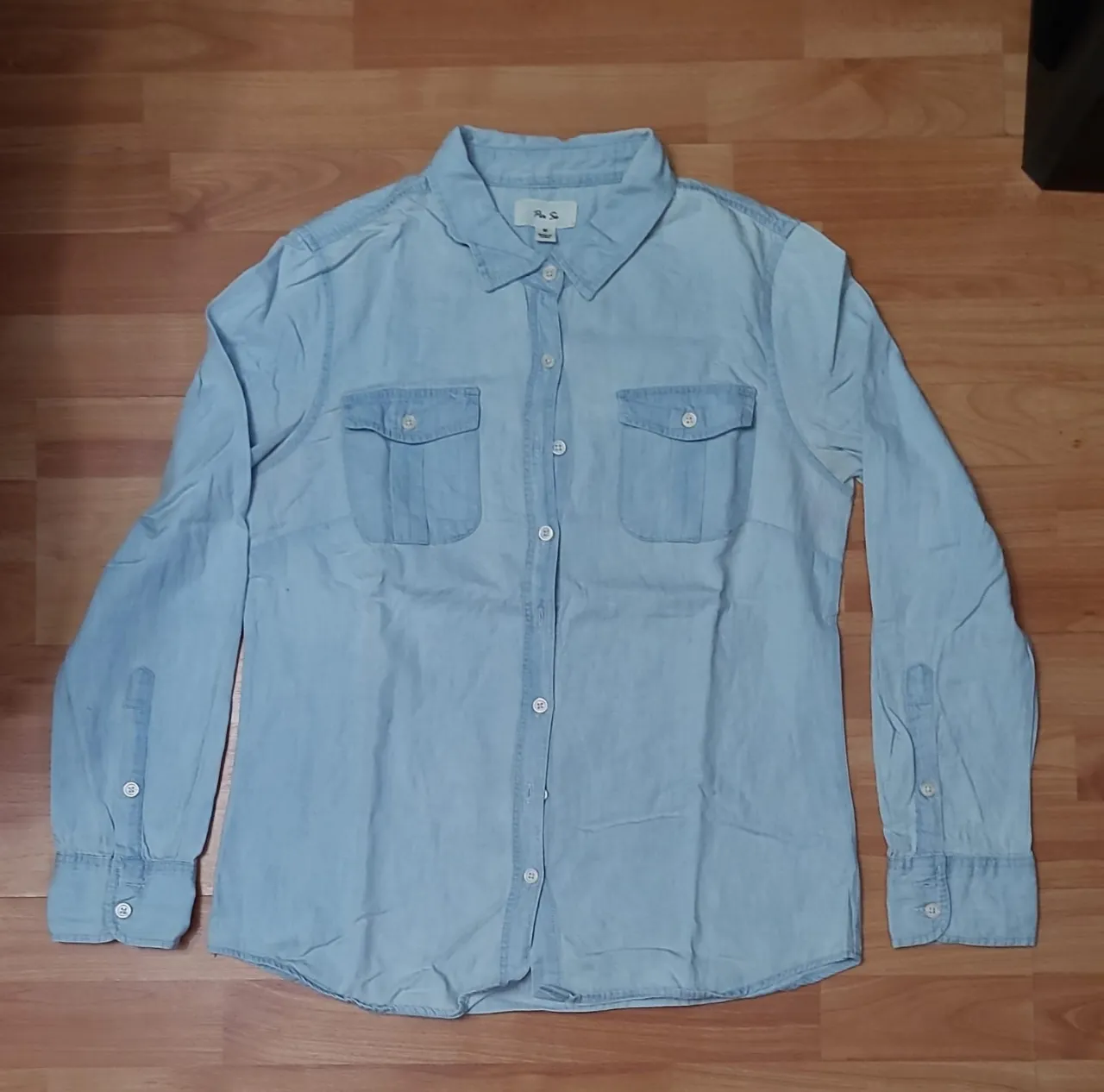 Camisa de jean celeste claro, de la marca Per Se, talle M. Con dos bolsillos delanteros y mangas largas con puños.
