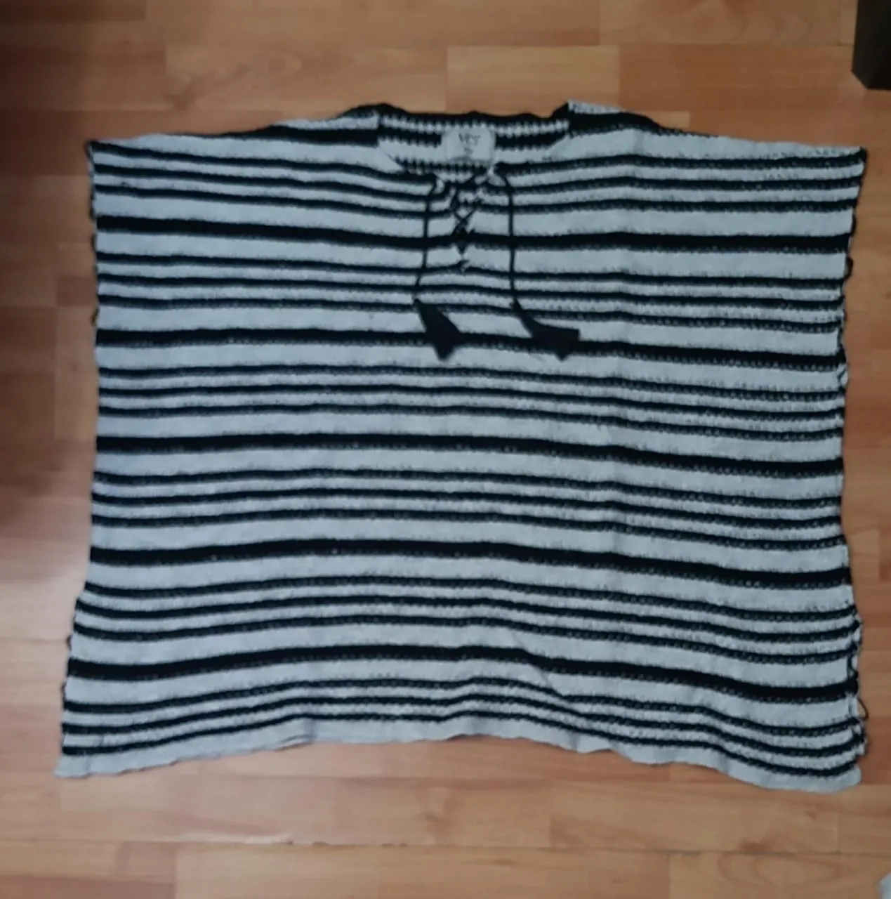 Blusa de mujer a rayas horizontales en blanco y negro, con detalle de cordones en el cuello y borlas. Ideal para un look casual y fresco.