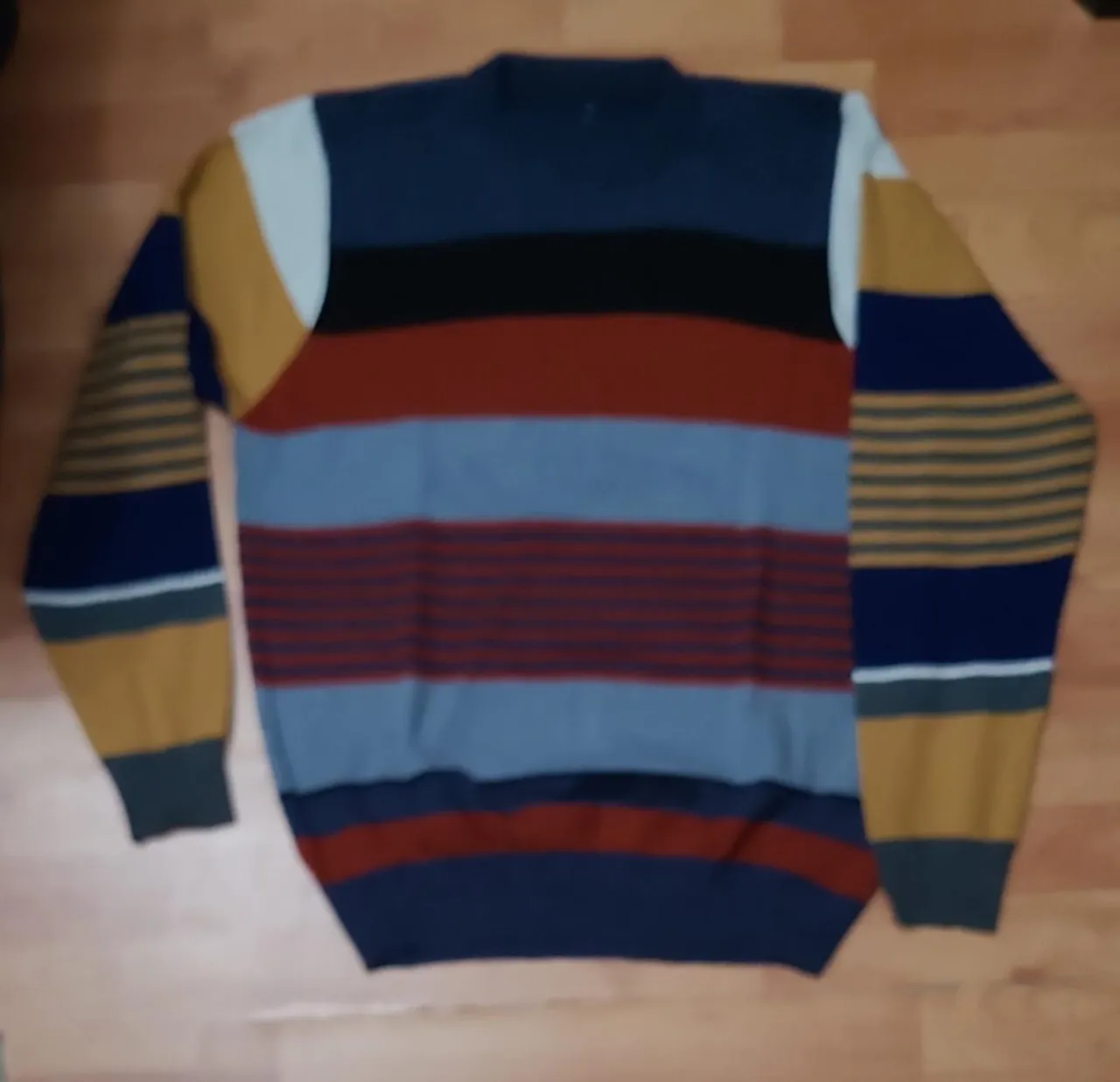 Sweater de hombre a rayas horizontales con cuello alto. Combina azul, negro, rojo, gris y amarillo. Ideal para un look casual y abrigado.