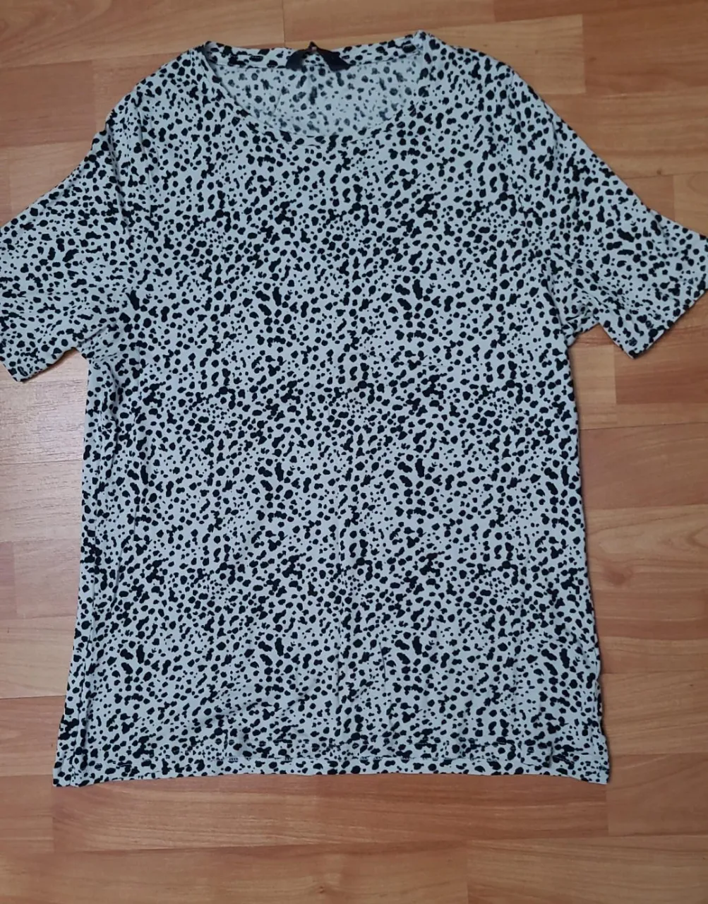 Remera de mujer con estampado de lunares en blanco y negro. Cuello redondo y manga corta. Ideal para un look casual y moderno.