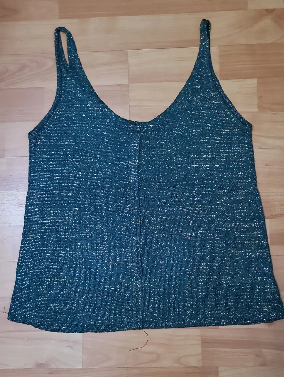 Top de mujer con diseño brillante en color verde oscuro y detalles dorados. Escote en V y tirantes finos. Ideal para un look de fiesta o salida.