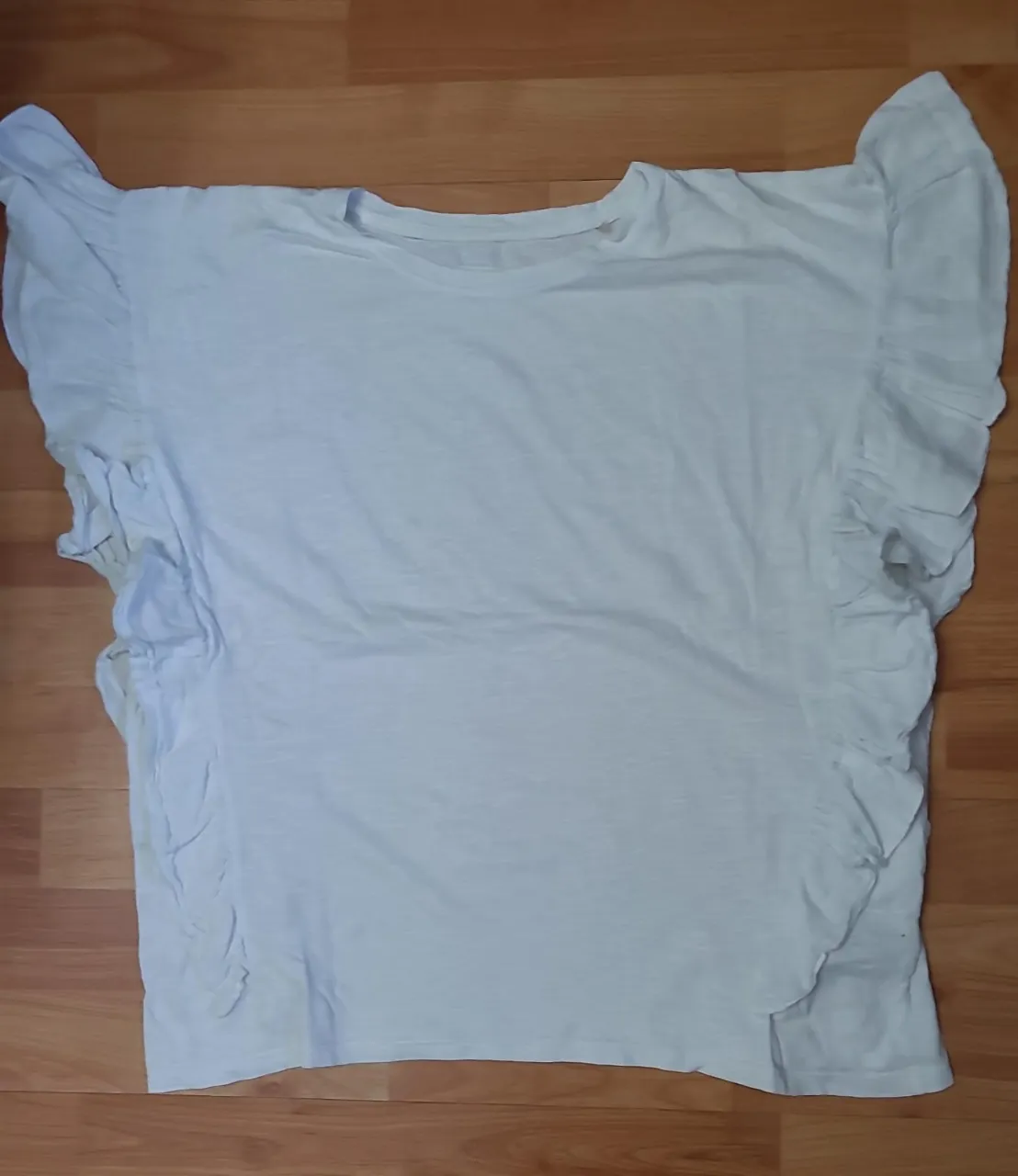 Blusa blanca con volados en las mangas, ideal para un look casual y fresco. Talle S.