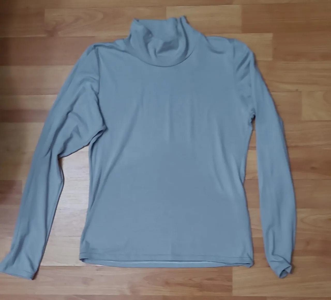 Remera de manga larga para mujer, con cuello alto. Ideal para usar como prenda base en invierno o en climas frescos. De color gris liso, versátil y fácil de combinar.