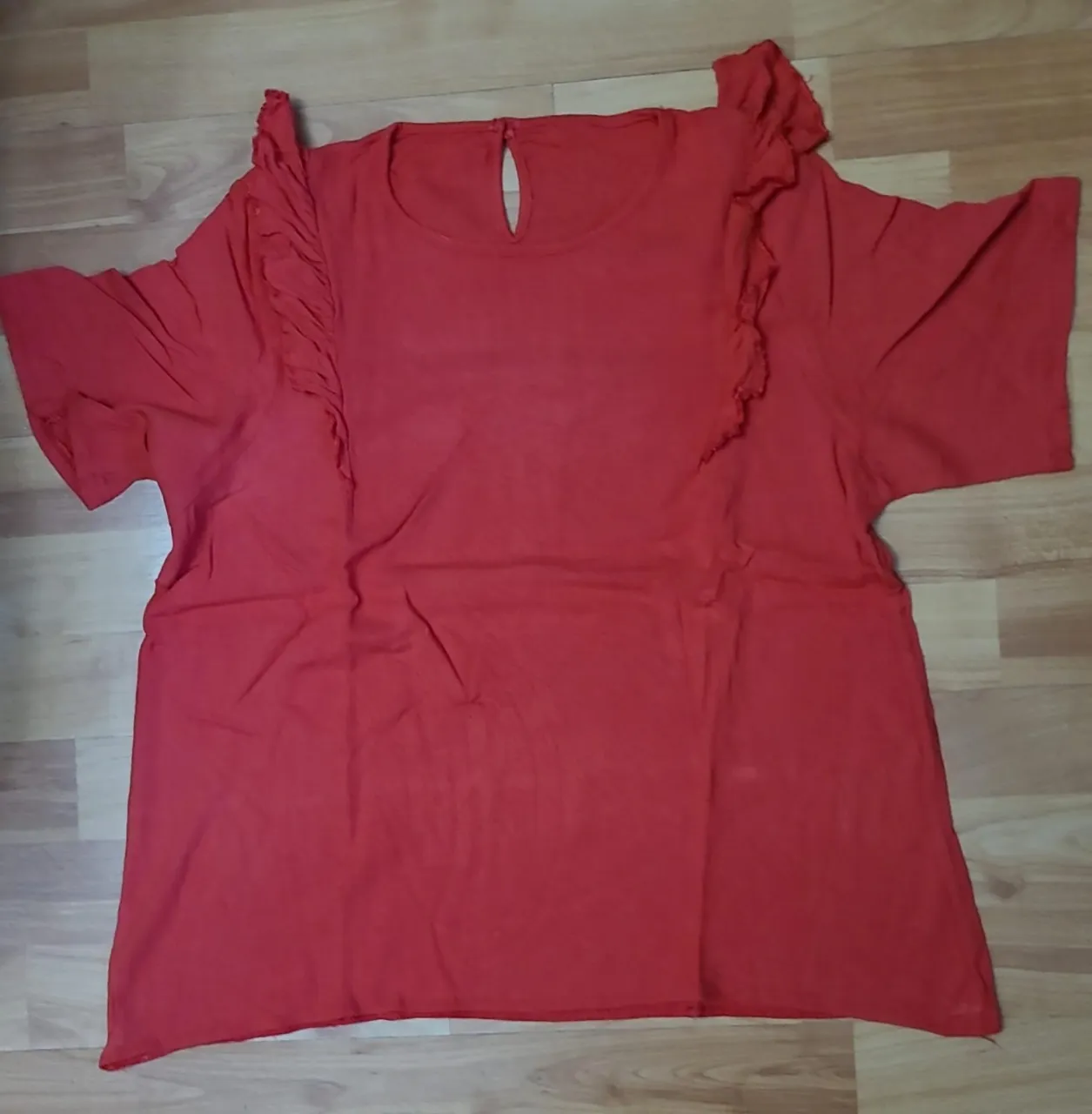 Blusa roja con detalle de volados en los hombros y escote redondo. Ideal para un look casual y femenino.