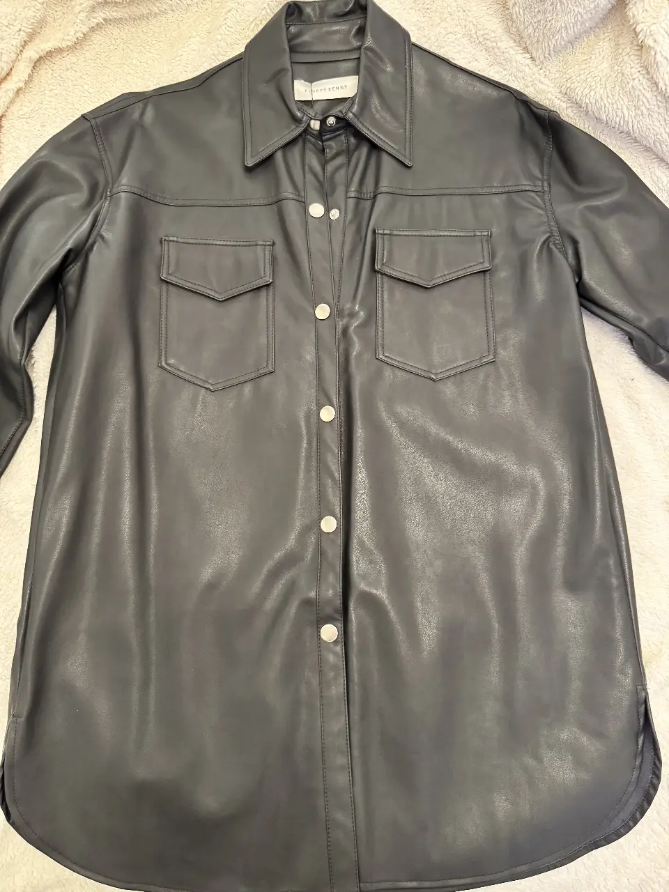 Camisa/camisaco de cuero sintético, color negra, de la marca Floppy Kenny. Con dos bolsillos delanteros y botones plateados. talle 1 (es un S o M). Ideal para un look moderno y sofisticado. 
