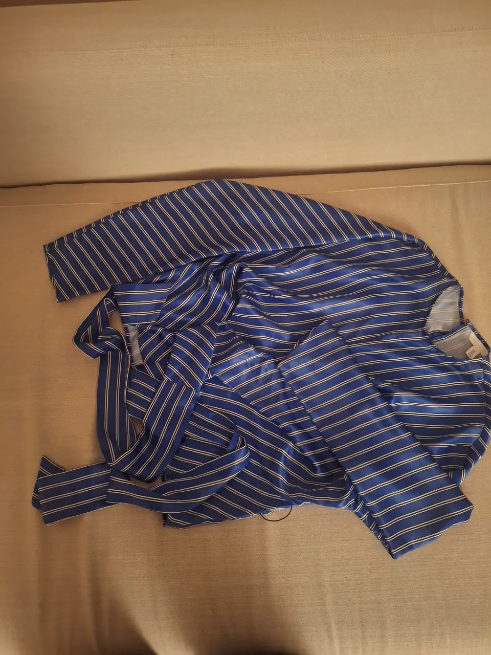 Camisa a rayas azul y blanca, con mangas largas y lazos para ajustar en la cintura. Ideal para un look casual y fresco.
