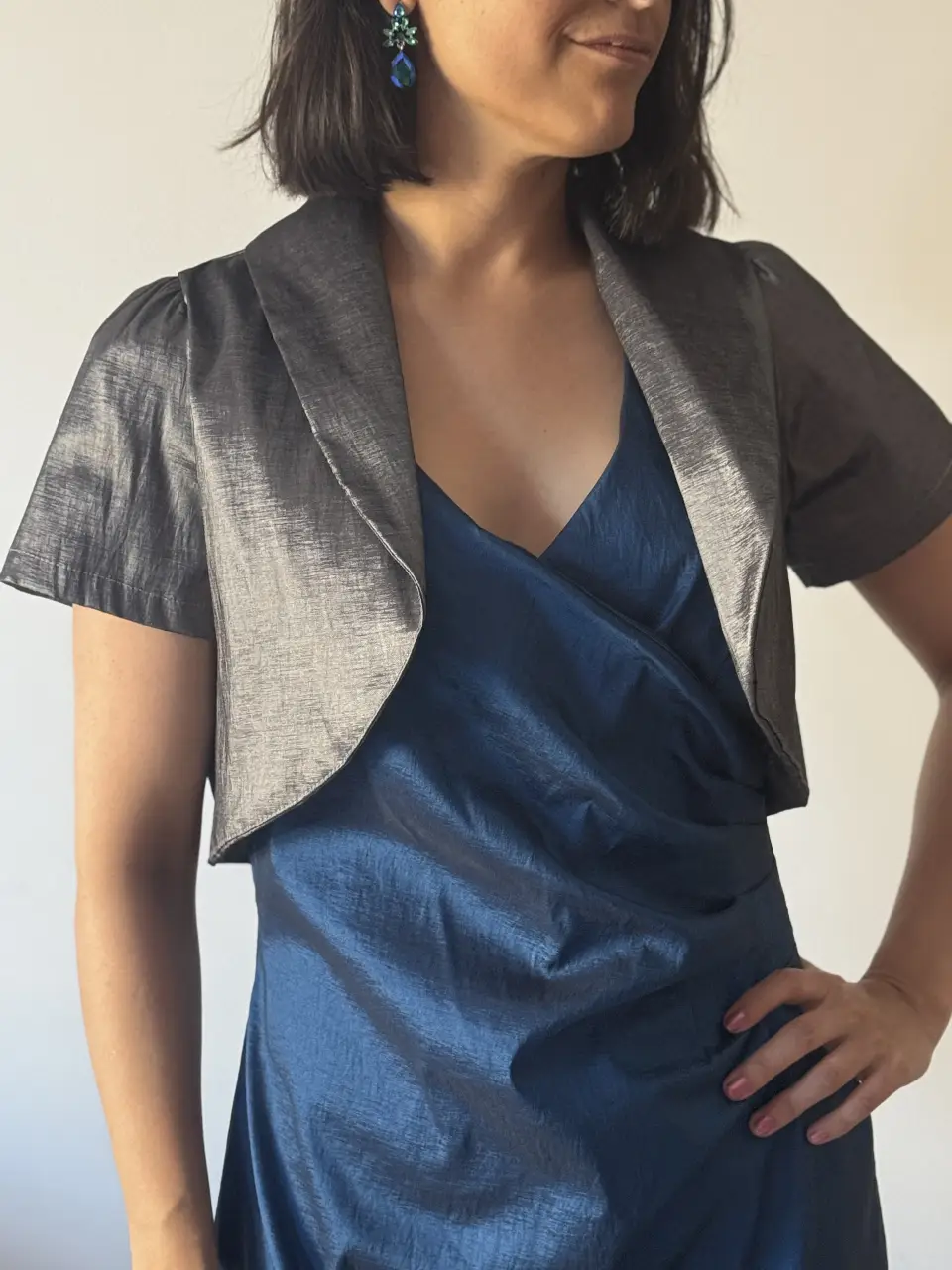 Elegante bolero plateado con solapas y mangas cortas. Ideal para complementar un vestido de fiesta o darle un toque sofisticado a cualquier look. 
