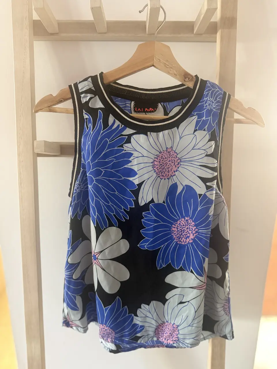 Musculosa de mujer con estampado floral en tonos azules y blancos sobre fondo negro. Diseño sin mangas, ideal para el verano. Perfecta para un look casual y fresco.