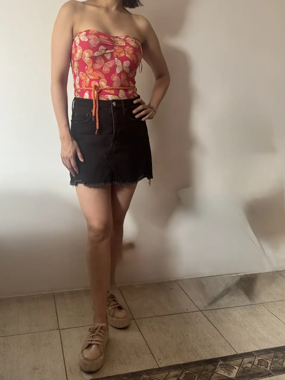 Minifalda de jean negra con detalles desflecados en el borde. Combinala con un top estampado para un look moderno y casual.